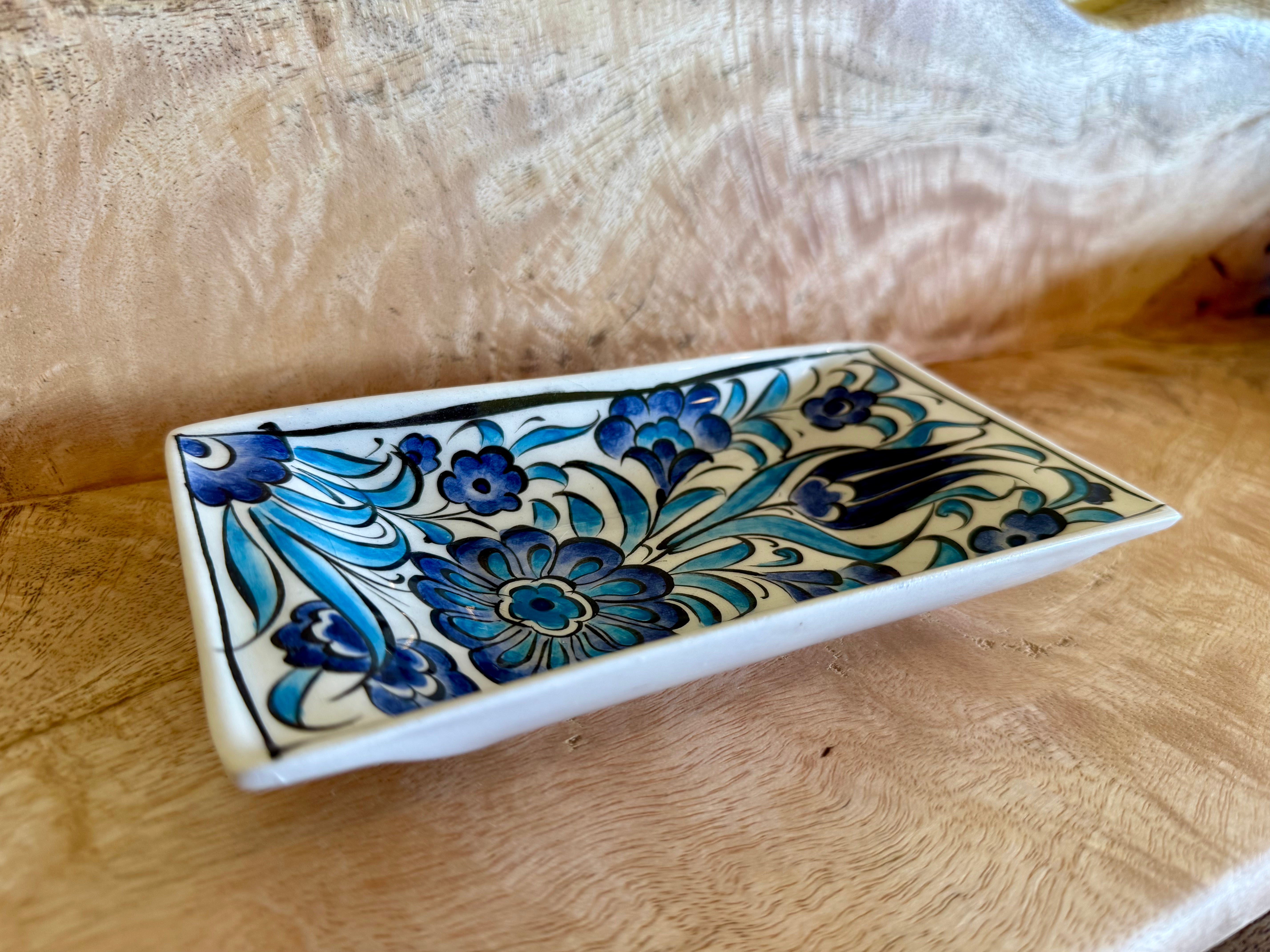A rectangular ceramic serving tray with a white base decorated in a blue and black floral pattern, resting on a light wood surface.