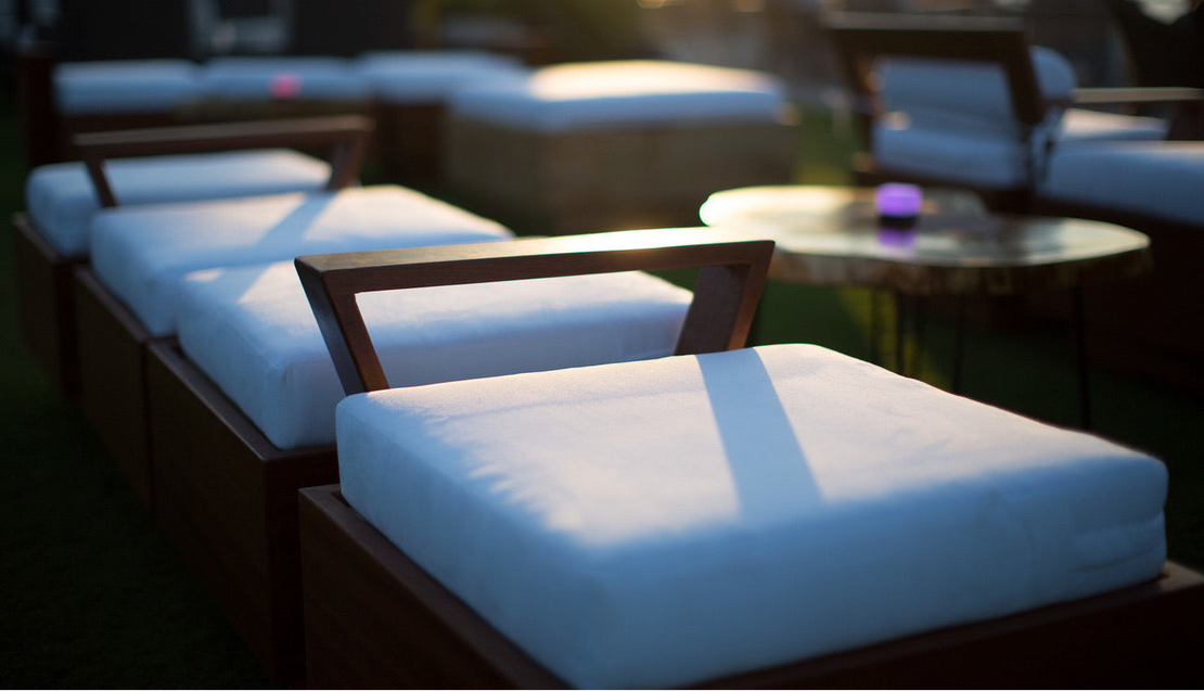 Outdoor seating area with cushions and a table at sunset.