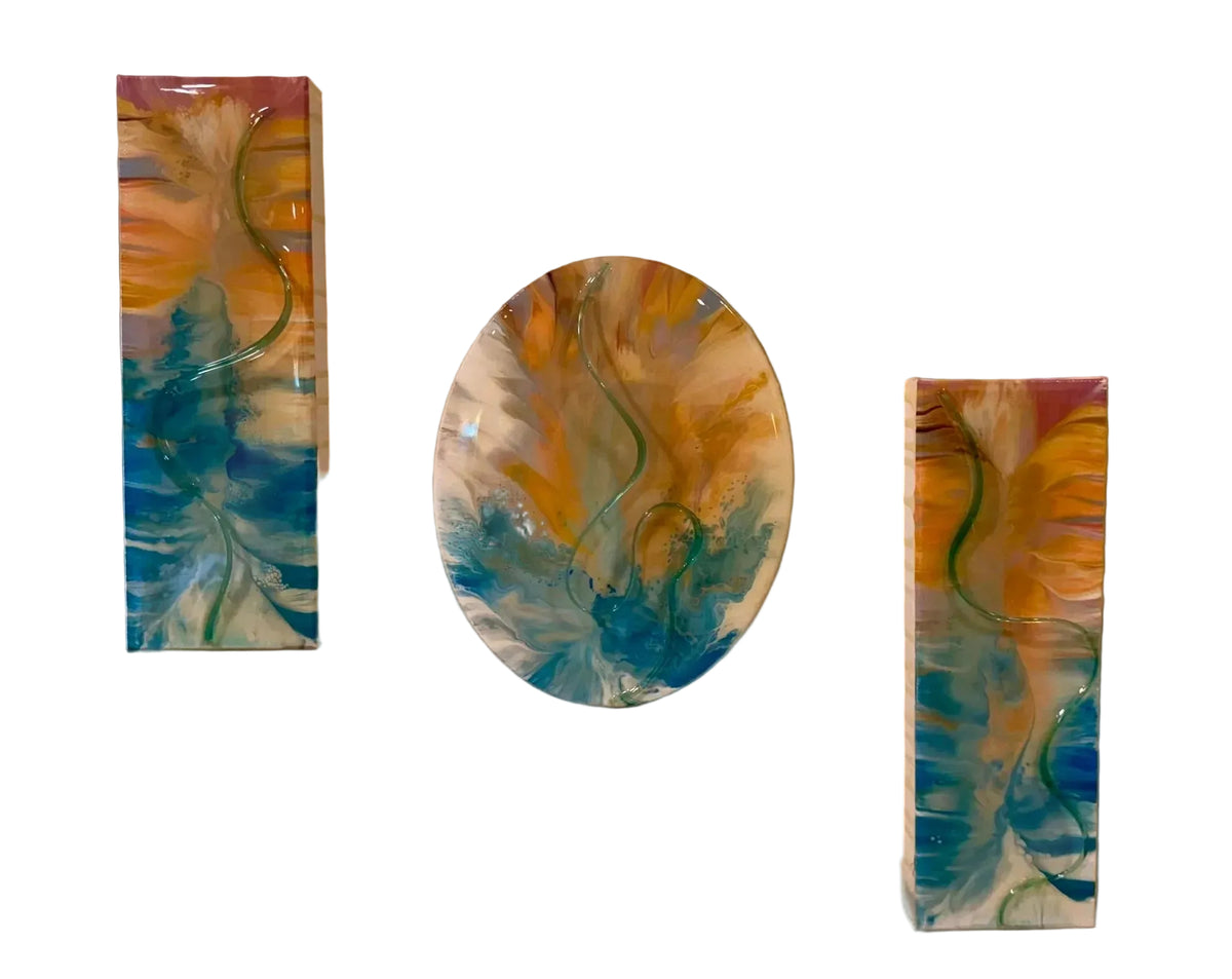 Three abstract wall art pieces displayed on a textured beige wall: one oval plaque in the center and two matching vertical rectangular panels on either side. The artwork features swirling marbled patterns in blue, orange, pink, white, and green.