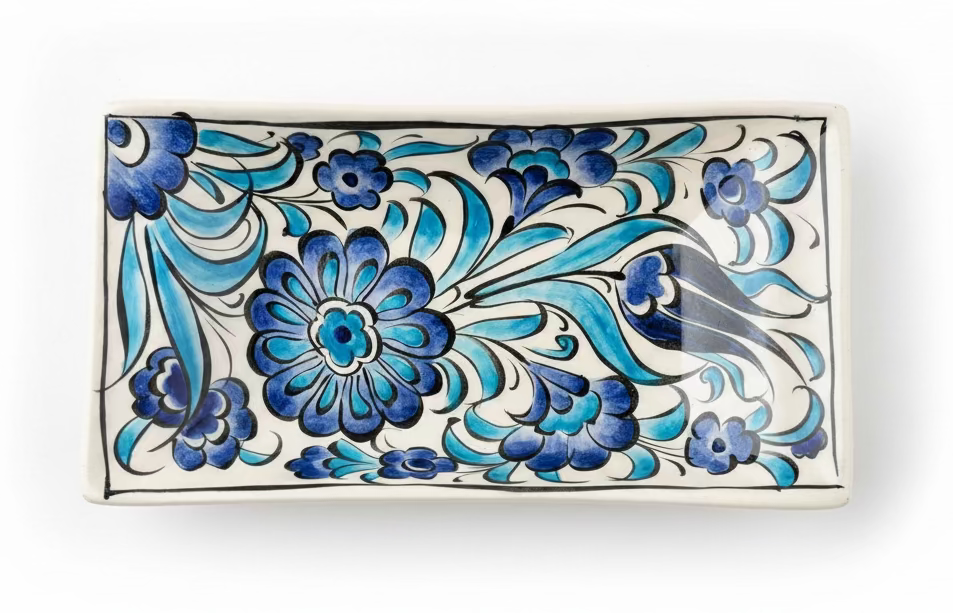 A rectangular ceramic dish with a hand-painted floral pattern in shades of blue, navy, and black on a white background, shown on a wooden surface with a ruler at the bottom indicating its size.