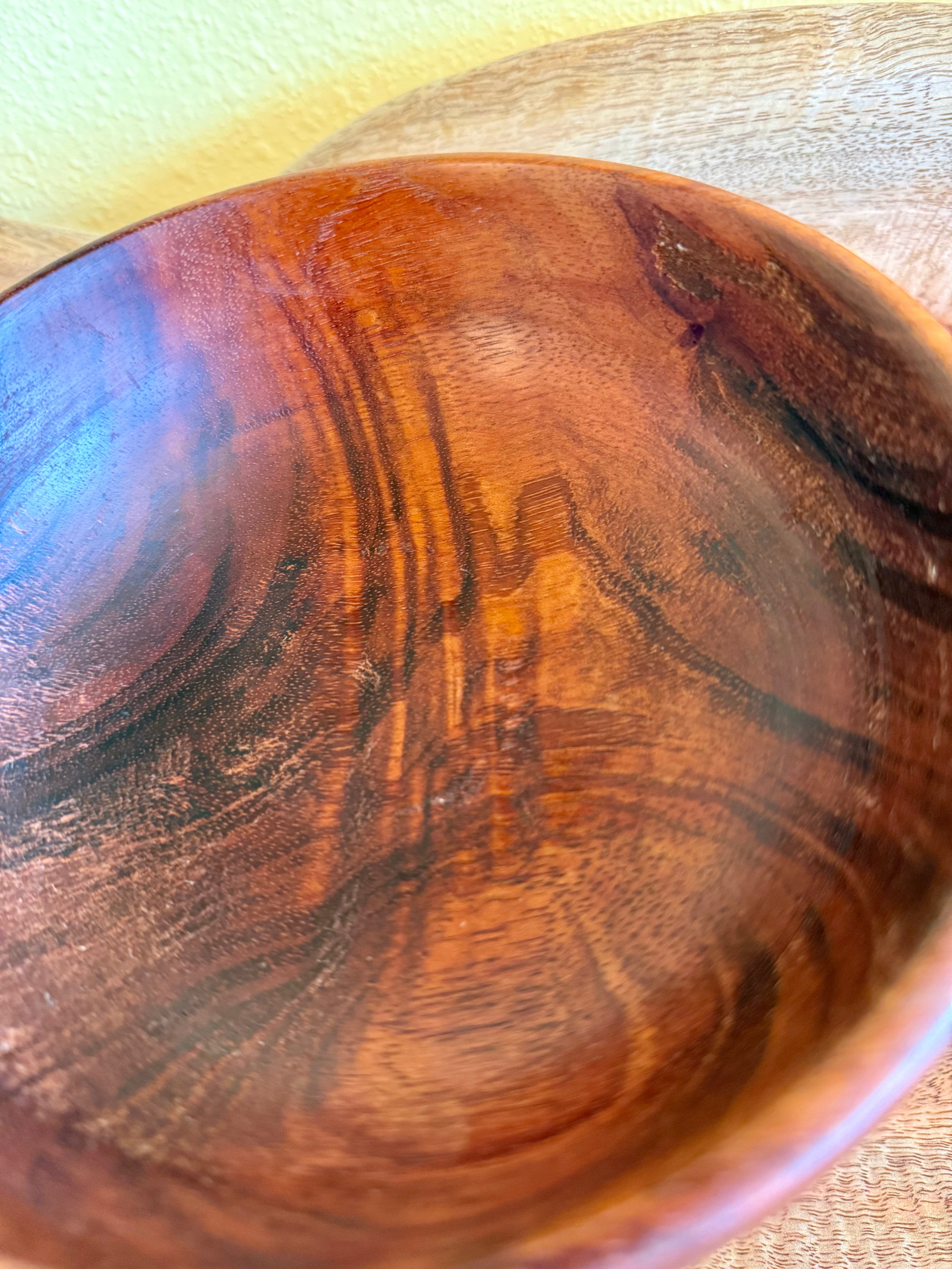 Close-up of the inside of a handcrafted wooden bowl with rich warm brown and amber tones and natural wood grain patterns. Hawaiian koa
