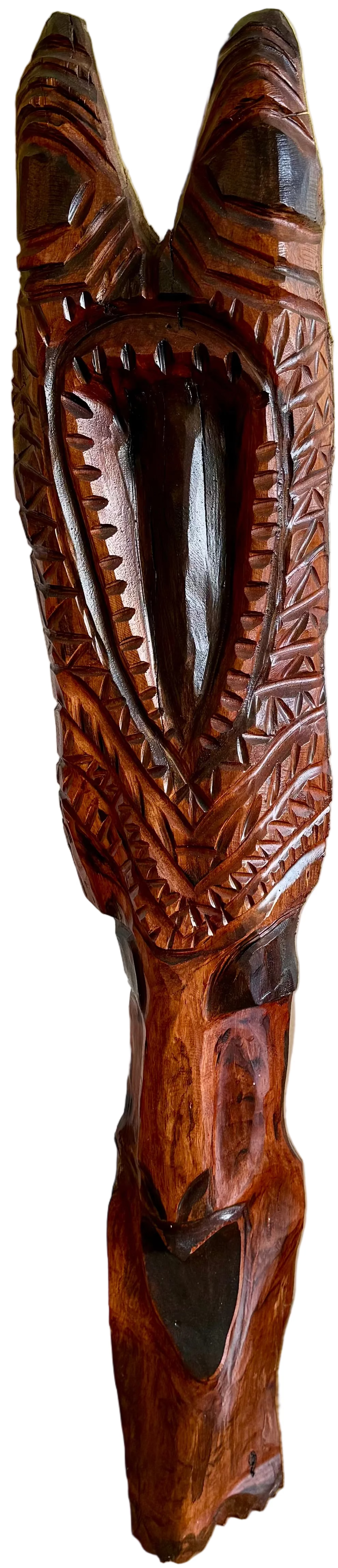 A carved wooden sculpture of a shark head with an open mouth showing sharp teeth, photographed indoors against a light wall and wood floor.