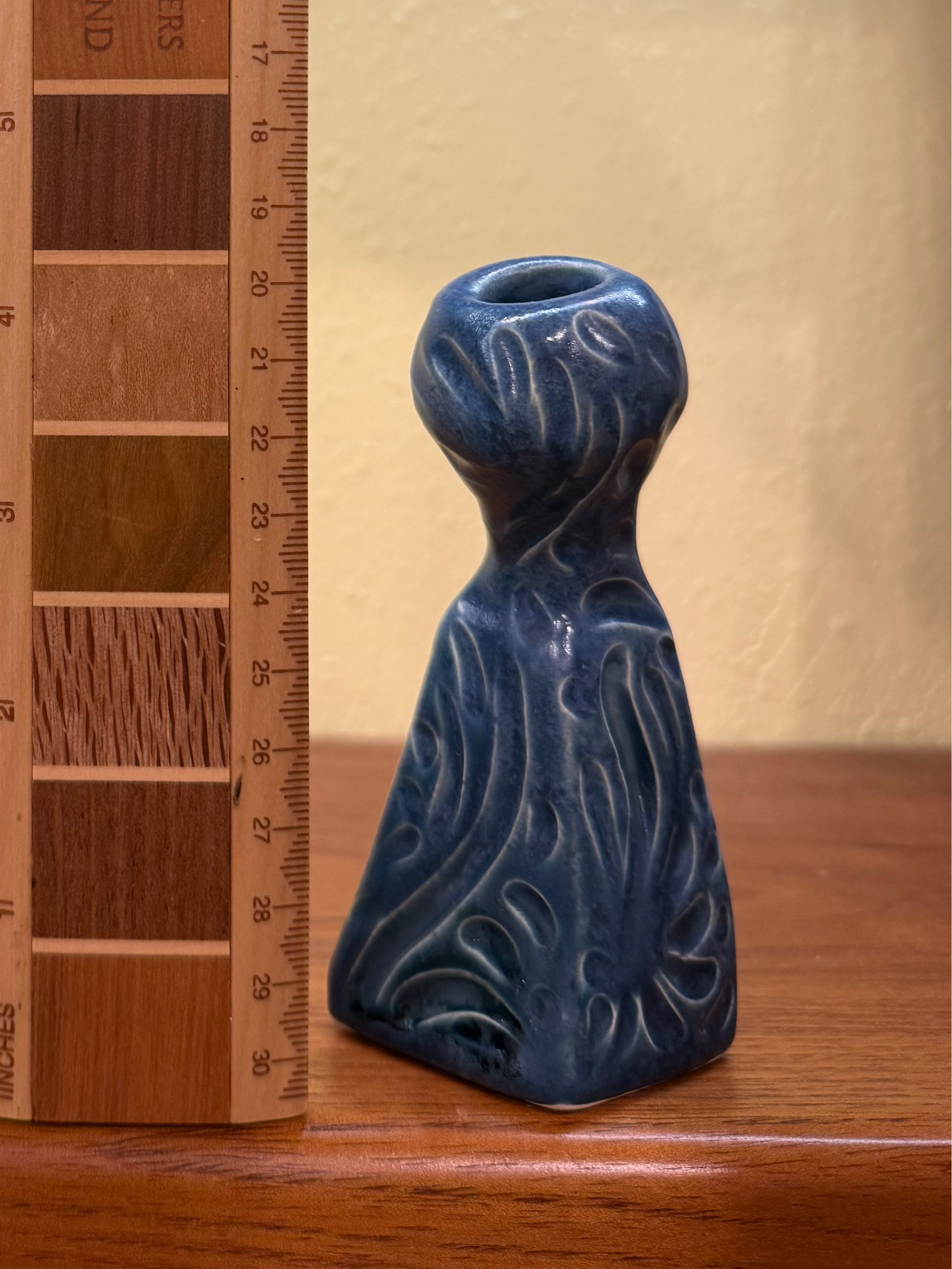 Two ceramic bird-shaped vases displayed on a wooden shelf next to a wooden ruler for scale. The larger vase on the left is light blue with a textured, scale-like pattern, while the smaller vase on the right is dark blue with a wavy, flowing pattern.