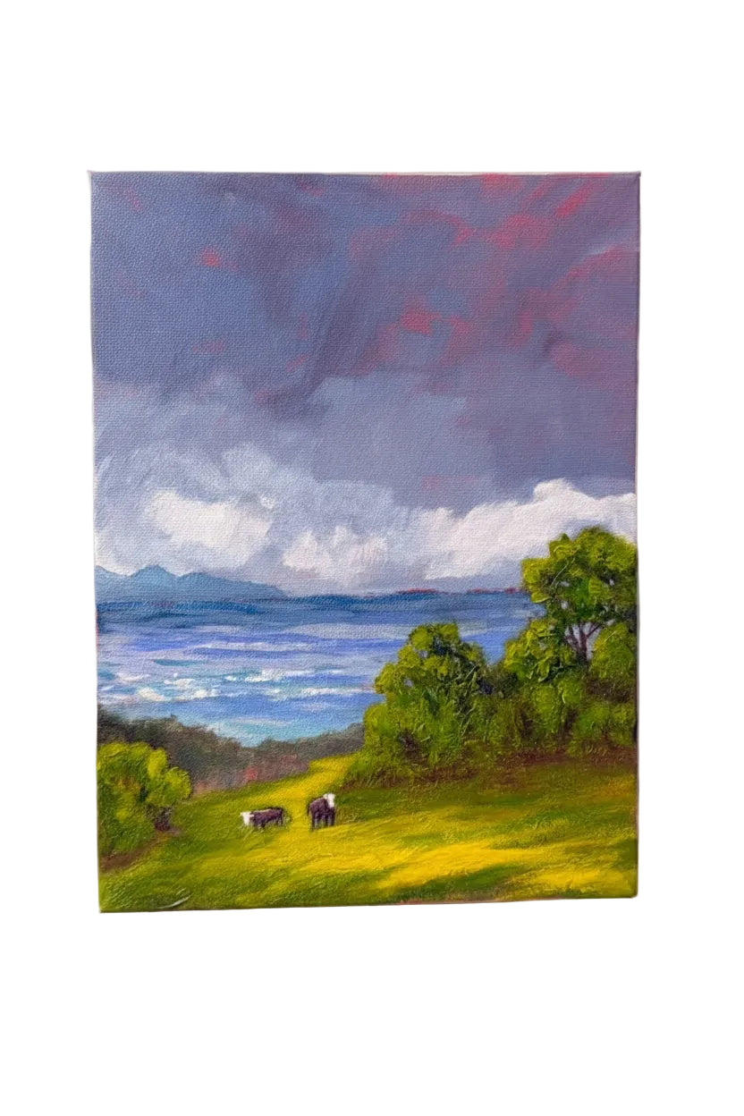 A landscape painting on canvas depicting a green hillside with grazing cows, trees, a blue sea, and mountains under a dramatic purple and pink cloudy sky, shown against a plain white background.