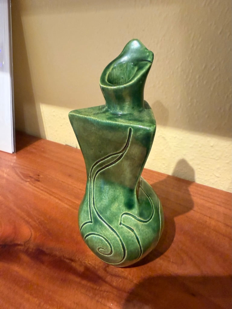 Green ceramic vase on a wooden surface with a neutral background