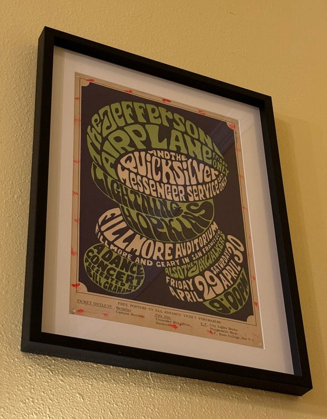 Framed rock and roll poster with text on a beige wall. jefferson airplane vintage rock and roll concert poster 