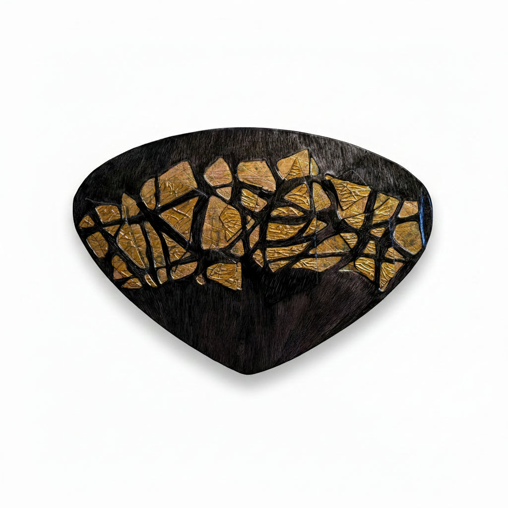 Decorative wall piece with black and gold mosaic design on a beige wall.