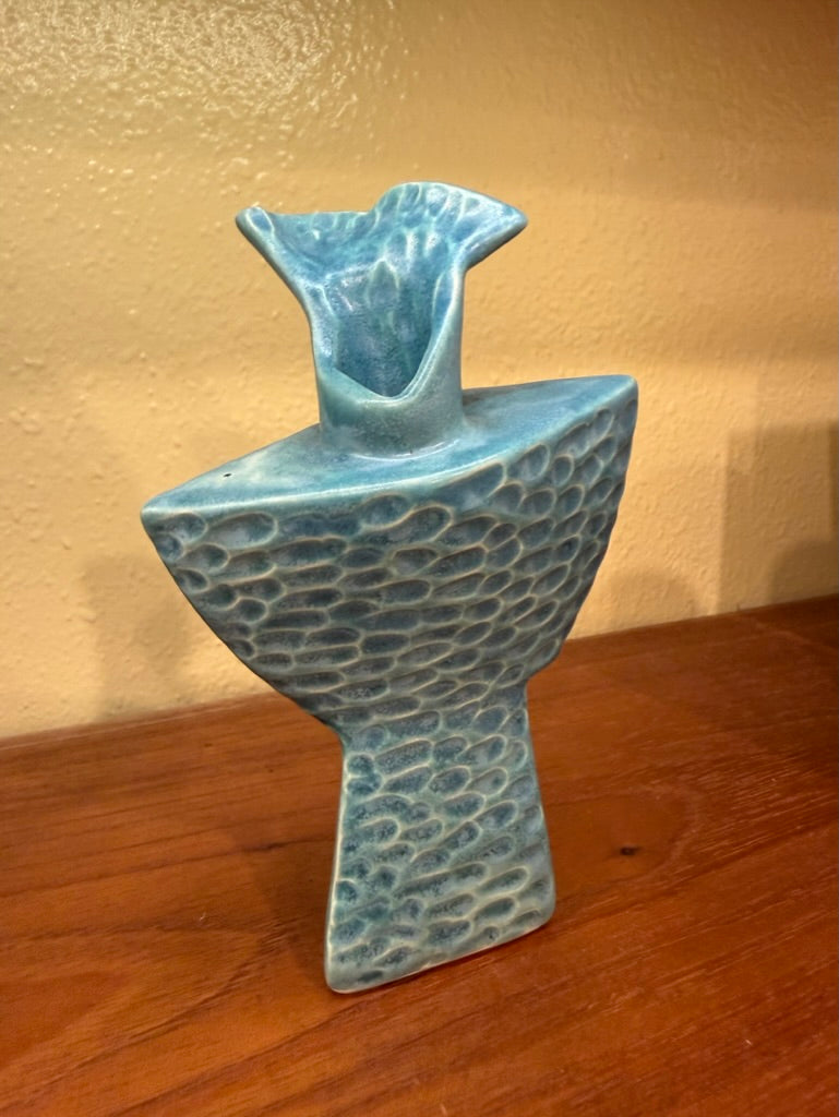 Blue textured vase on a wooden surface with a gold background