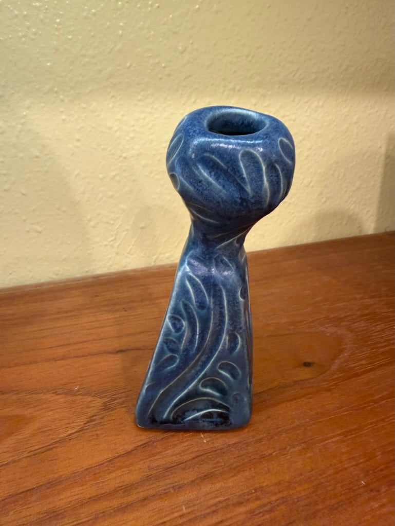 Blue ceramic candle holder on a wooden surface with a beige wall background