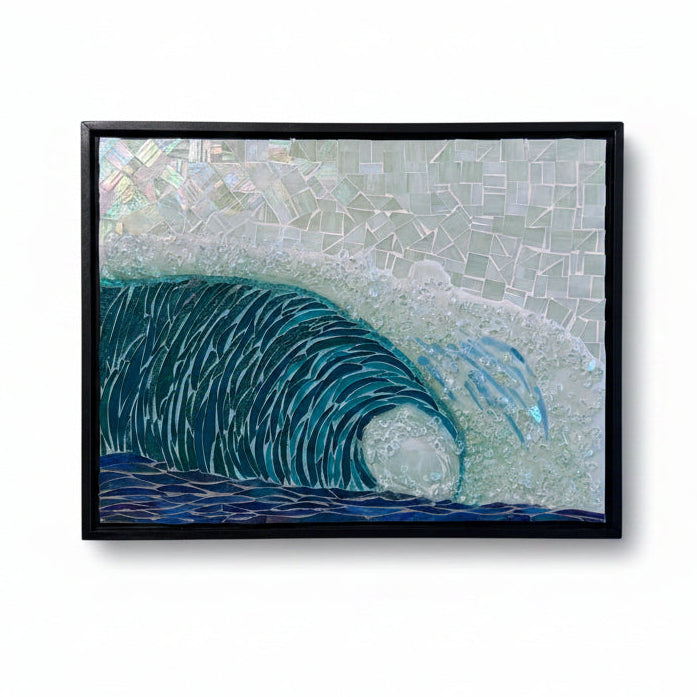 A framed mosaic art print depicting a curling ocean wave in shades of blue and green, set against a light gray textured background with a black frame.