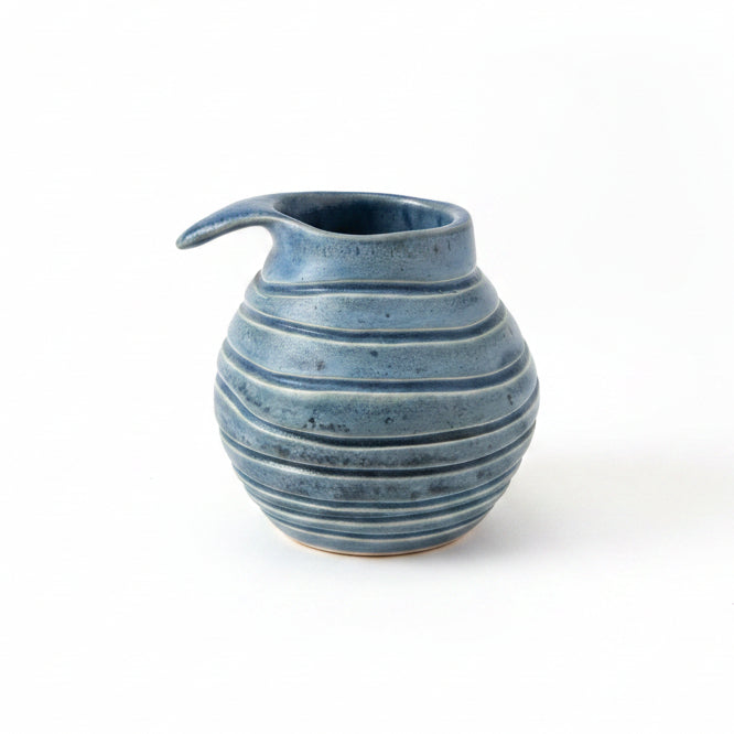 Blue ceramic vase on a wooden surface with a beige wall background