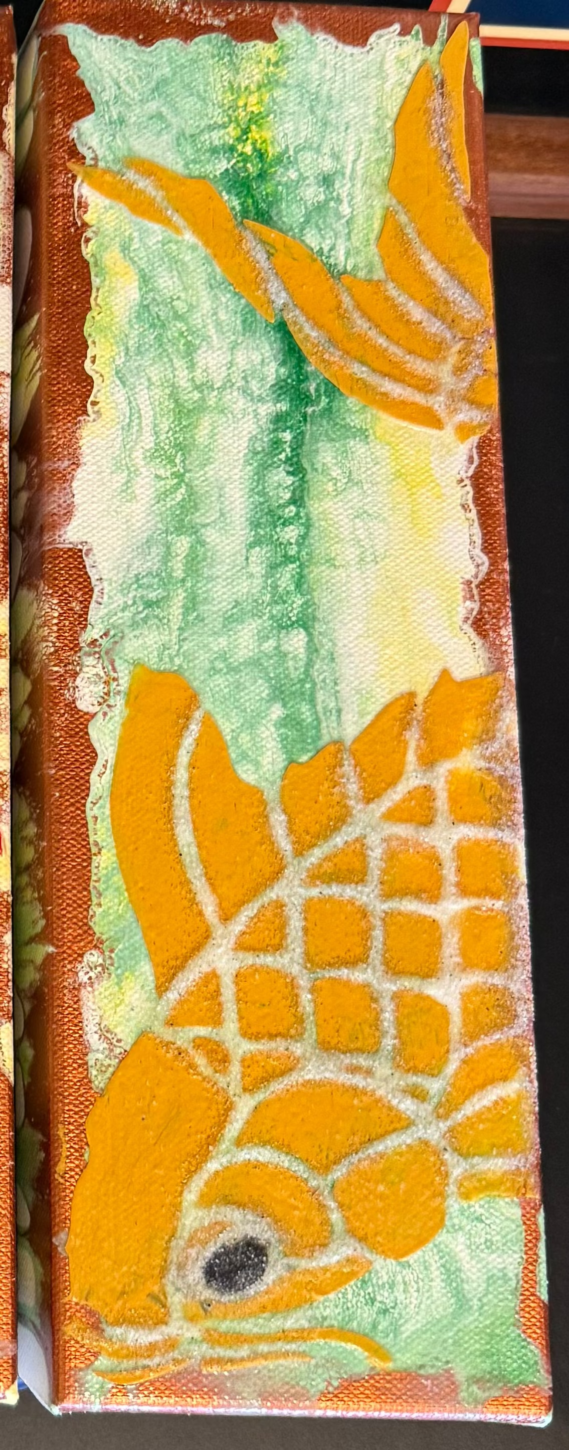 Three rectangular artworks with fish and nature-themed designs on a dark surface.